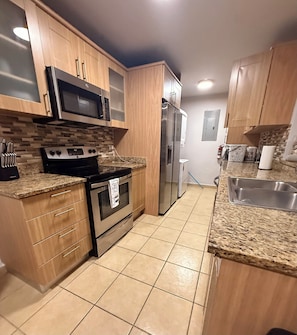 Una cocina moderna con gabinetes de madera, un refrigerador de acero inoxidable, un microondas y una estufa.
