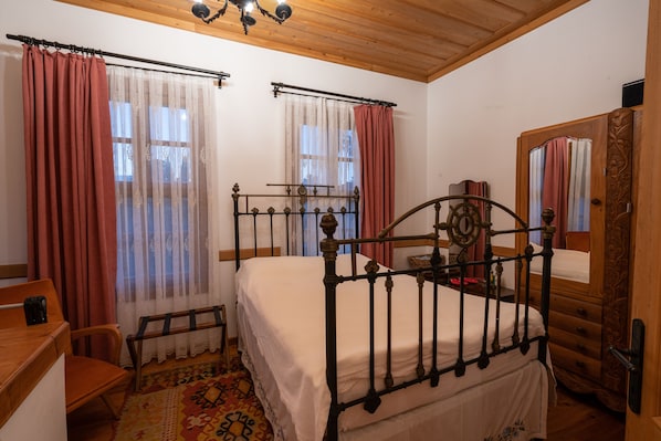A bedroom with two beds, a wooden headboard, a wooden dresser, a chair, and a patterned rug.