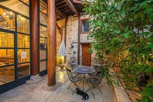 Un patio al aire libre con suelo de piedra, una pérgola de madera y una mesa con sillas.