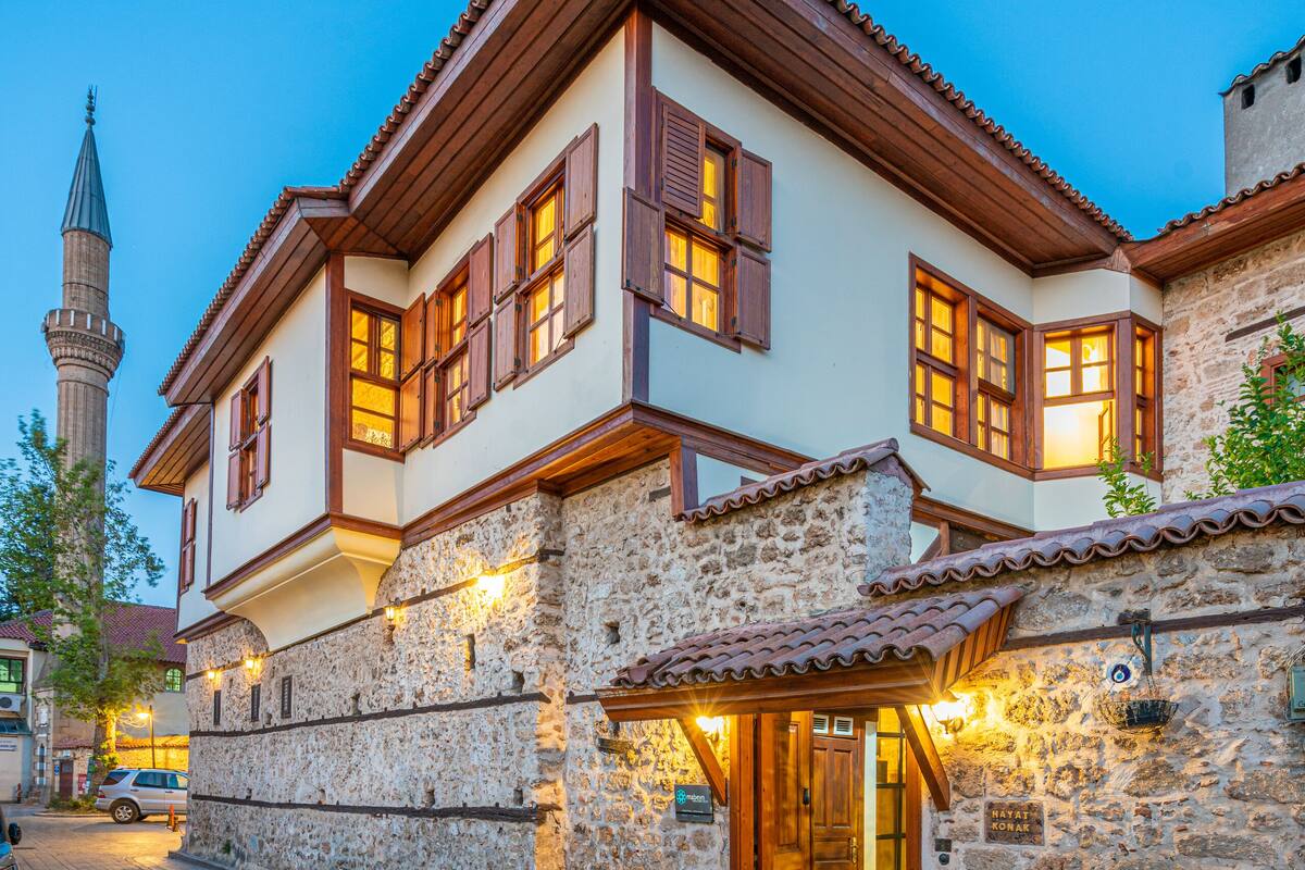 A traditional building with a stone facade, wooden shutters, and a tiled roof.