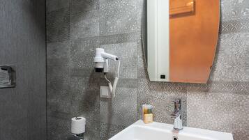 Une salle de bain équipée de toilettes, d’un lavabo, d’un porte-serviettes et d’un miroir.