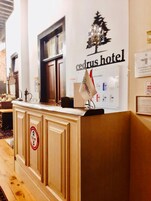 Una mesa de recepción en el Hotel Cedrus, con un cartel que indica los números de habitación y una decoración navideña.