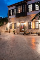 Un edificio de piedra con patio, mesas al aire libre y un letrero que dice