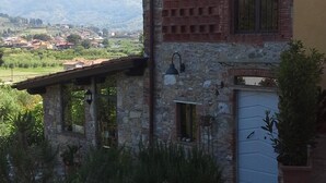 Un bâtiment en pierre avec un toit en tuiles, un escalier en pierre et une vue sur une vallée.