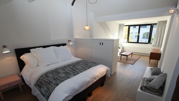 Ein Schlafzimmer mit Bett, Nachttisch, Kleiderschrank und Blick ins Freie.