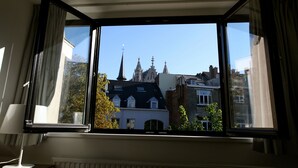 Ein Zimmer mit großem Fenster mit Blick auf ein historisches Gebäude mit mehreren Türmen.