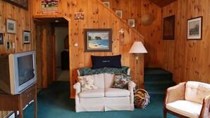A cozy wooden interior with a sofa, a television, and a staircase. - Enjoy Sunset views on tranquil Dexter Pond (Winthrop)