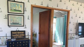Una habitación con puerta de madera, un escritorio con computadora y papel tapiz con motivos náuticos.