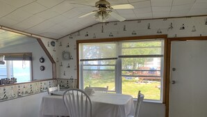 Comedor con mesa y sillas, ventilador de techo y vista al exterior.