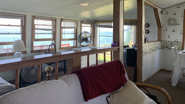 Una habitación con un banco de madera, una manta roja y vistas al mar a través de amplios ventanales.