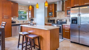 Una cocina moderna con armarios de madera, electrodomésticos de acero inoxidable y una isla central con taburetes.