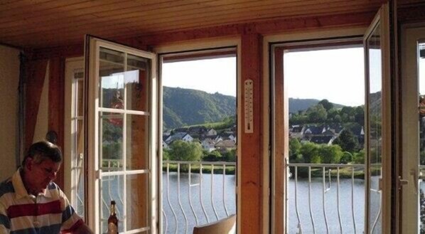 A room with a wooden ceiling, a window with a view of a lake and hills, and a door with a sign. - Gorgeous bright Riverside Apartments, Zell Mosel, At Hahn Airport bus line (Zell (Mosel))