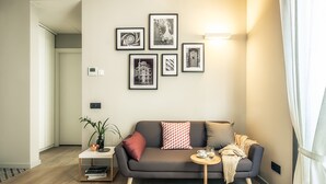 A modern living room with a grey sofa, a small round table, and a potted plant.