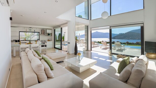 A modern living room with a large sofa, a coffee table, and a view of a pool and mountains. - Villa Setara is a rare beach front property located in Kalkan (Kalkan)