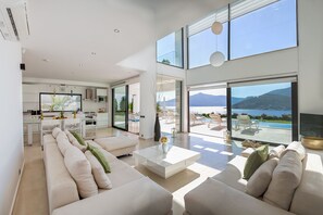 A modern living room with a large sofa, a coffee table, and a view of a pool and mountains. - Villa Setara is a rare beach front property located in Kalkan (Kalkan)