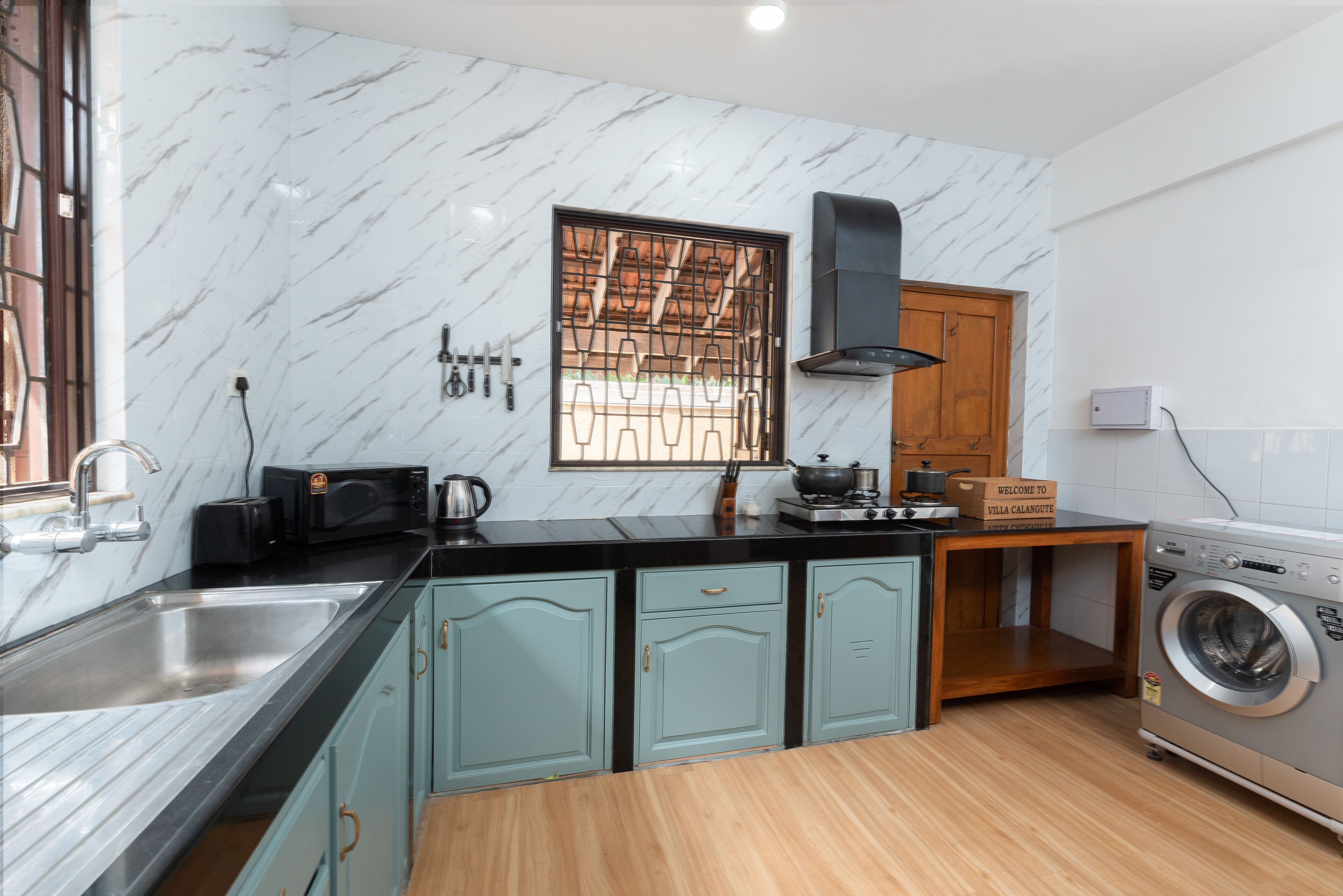 Una cocina con paredes de mármol, un lavabo, un microondas, una estufa y una lavadora.