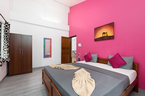 Un dormitorio con cama, dos almohadas, una colcha, un armario y un cuadro en la pared.