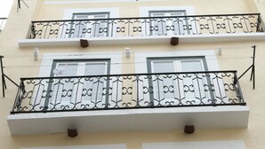 Un edificio de varios pisos con balcones, marcos de ventanas blancos y barandillas de metal decorativo.