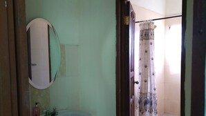Un bagno con un lavandino bianco, uno specchio e una zona doccia con tenda.
