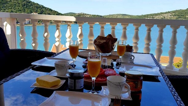 Une table dressée pour le petit-déjeuner, avec une vue sur un plan d’eau et des collines en arrière-plan.