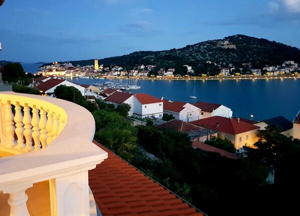 A coastal town with a prominent hill, a marina with boats, and buildings with red roofs.