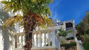 Un escalier en pierre mène à un bâtiment blanc doté d’un balcon.
