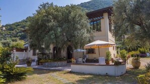 Une villa dotée d’un patio, d’un espace salon extérieur et offrant une vue sur une colline.