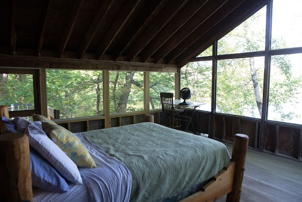 Une chambre dans une cabane en bois, avec un lit, un bureau et une chaise.