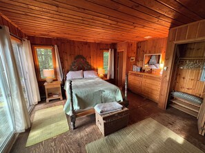 Une chambre à coucher dans une cabane en bois, avec un lit à baldaquin, une commode, un miroir et un banc.