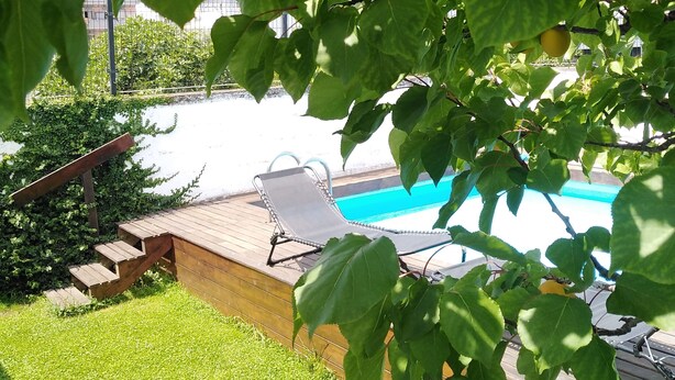 Ett område vid poolen med ett trädäck, en solstol och en swimmingpool.