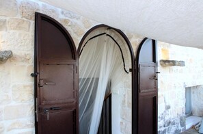 A stone building with arched doors and a covered entrance. - Trulli e Masseria Ianella (Locorotondo (Bari))