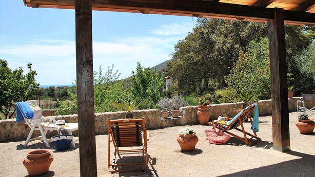 An outdoor patio with wooden furniture, terracotta pots, and a view of a mountainous landscape. - VILLA CYCAS relaxation between sea and nature (Itri)