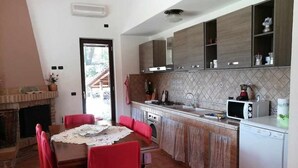 A kitchen with a dining table, chairs, a microwave, a stove, and a dishwasher. - VILLA CYCAS relaxation between sea and nature (Itri)