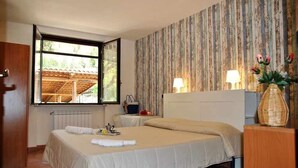 A bedroom with a large bed, a window, a radiator, a nightstand, and a lamp. - VILLA CYCAS relaxation between sea and nature (Itri)