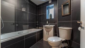 A modern bathroom with a bathtub, sink, and toilet.