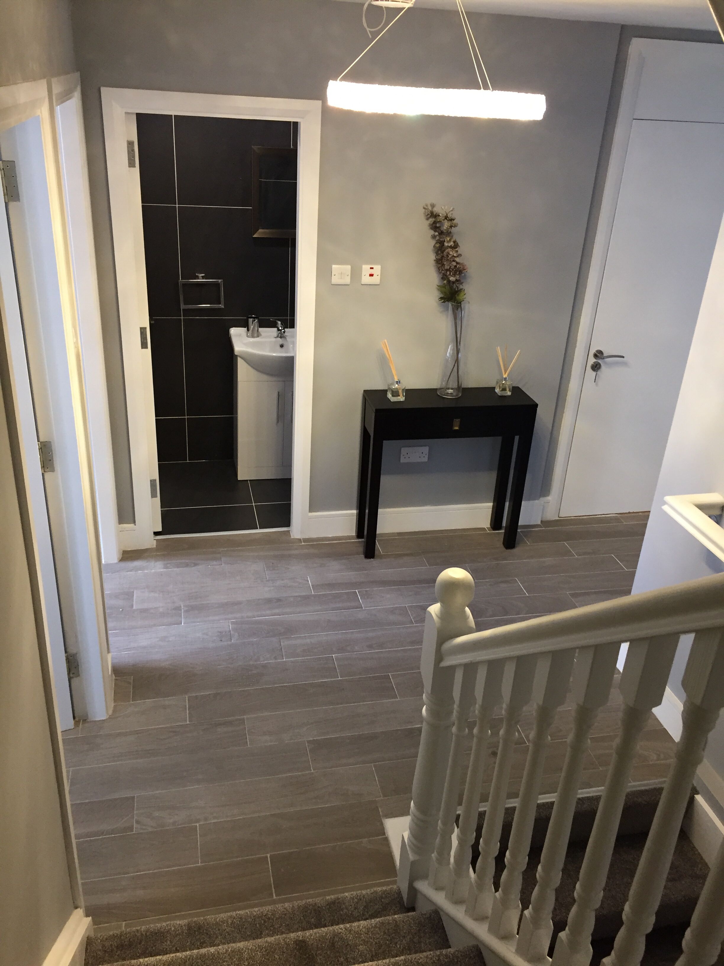 A staircase leading to a bathroom with a sink and a black vanity table.