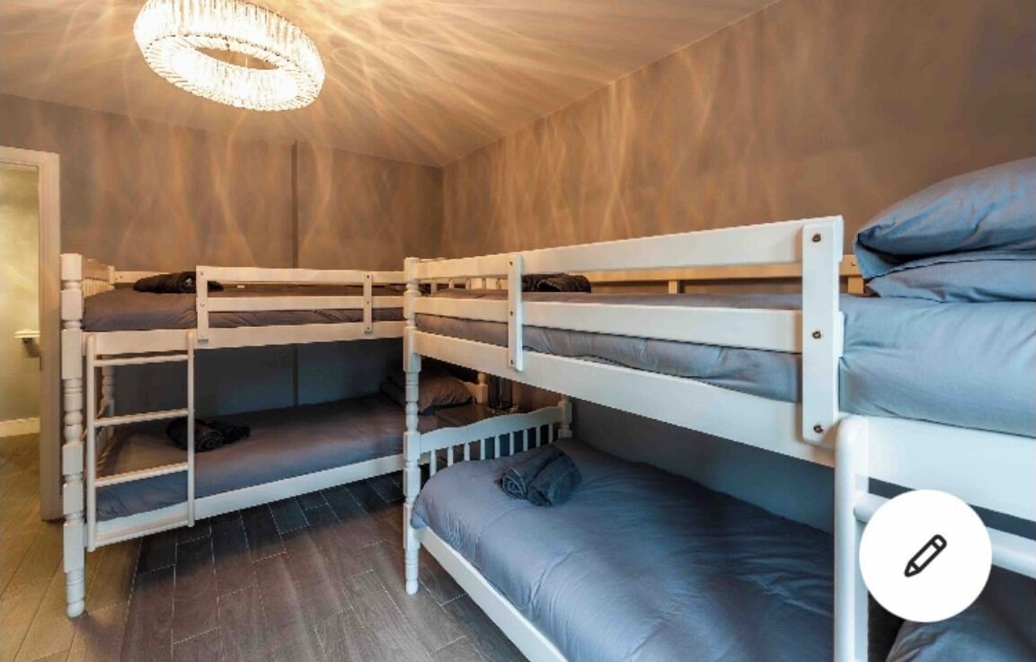 Habitación con literas, candelabro, paredes de madera y suelo de baldosas.