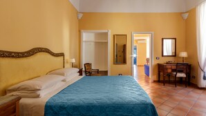 A hotel room with a large bed, a desk with a chair, a wardrobe, and a mirror. - La Rotonda Deluxe Apartment (Nerano)