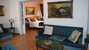 A living room with a blue sofa, a coffee table, and a painting of a bridge. - Minoa Downtown  Garden villa (Κουνουπιδιανά)