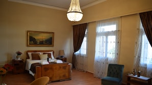 A bedroom with a wooden bed, a chair, a nightstand, a lamp, and a painting on the wall. - Minoa Downtown  Garden villa (Κουνουπιδιανά)