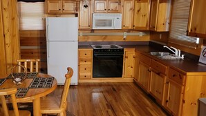 A wooden kitchen with a refrigerator, microwave, stove, and sink. - Cozy Log Cabin Getaway Waynesville, Smokey Mountains, Blue ridge Parkway (Canton)