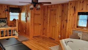 A cabin interior with a loft bed, a bench, a bathtub, and a ceiling fan. - Cozy Log Cabin Getaway Waynesville, Smokey Mountains, Blue ridge Parkway (Canton)