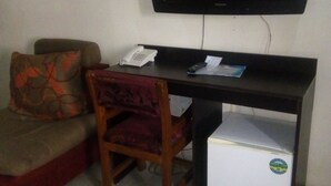 A small room with a desk, a chair, a television mounted on the wall, and a refrigerator. - Pridemark Hotel (Abuja)
