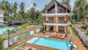 A two-story resort with a swimming pool, lounge chairs, and a tropical garden. - Private Balinese Style Villa With ZEN Garden and Swimming Pool (Calangute)