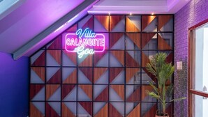 A hotel entrance with a neon sign reading "Villa Calangute Goa," a geometric wooden partition, and a potted plant. - Private Balinese Style Villa With ZEN Garden and Swimming Pool (Calangute)