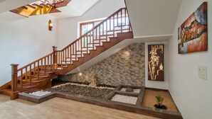 A modern staircase with wooden railings, a stone wall, and a small garden area with a Buddha statue and plants. - Private Balinese Style Villa With ZEN Garden and Swimming Pool (Calangute)