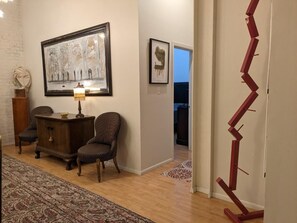 Um quarto com um tapete estampado, um armário de madeira, duas cadeiras listradas e uma obra de arte emoldurada na parede.