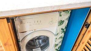 A compact laundry room with a built-in washer and dryer, wooden cabinets, and a tiled floor. - Marina Timone (Marina di Ragusa)