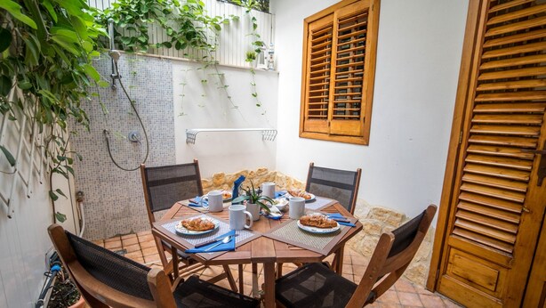 A dining area with a round table set for four, surrounded by chairs. - Marina Timone (Marina di Ragusa)