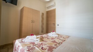 A hotel room with a bed, a wardrobe, and a flat-screen TV mounted on the wall. - Marina Timone (Marina di Ragusa)